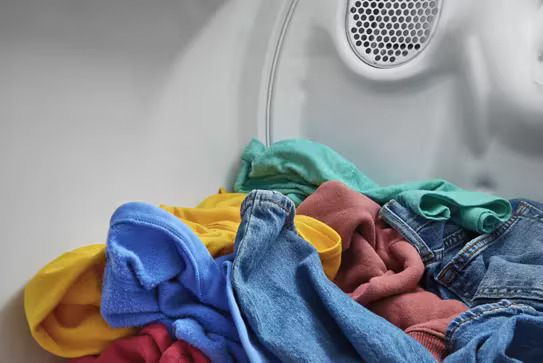 Close-up of colorful laundry tumbling inside a white Whirlpool dryer drum.